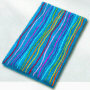 multi color novelty bath rug with fun colored stripes running over a solid background of either black, white or turquoise