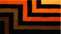Colorful geometric stripes ranging from dark brown and deep dark orange/rust to medium and light orange with black stripes in between.